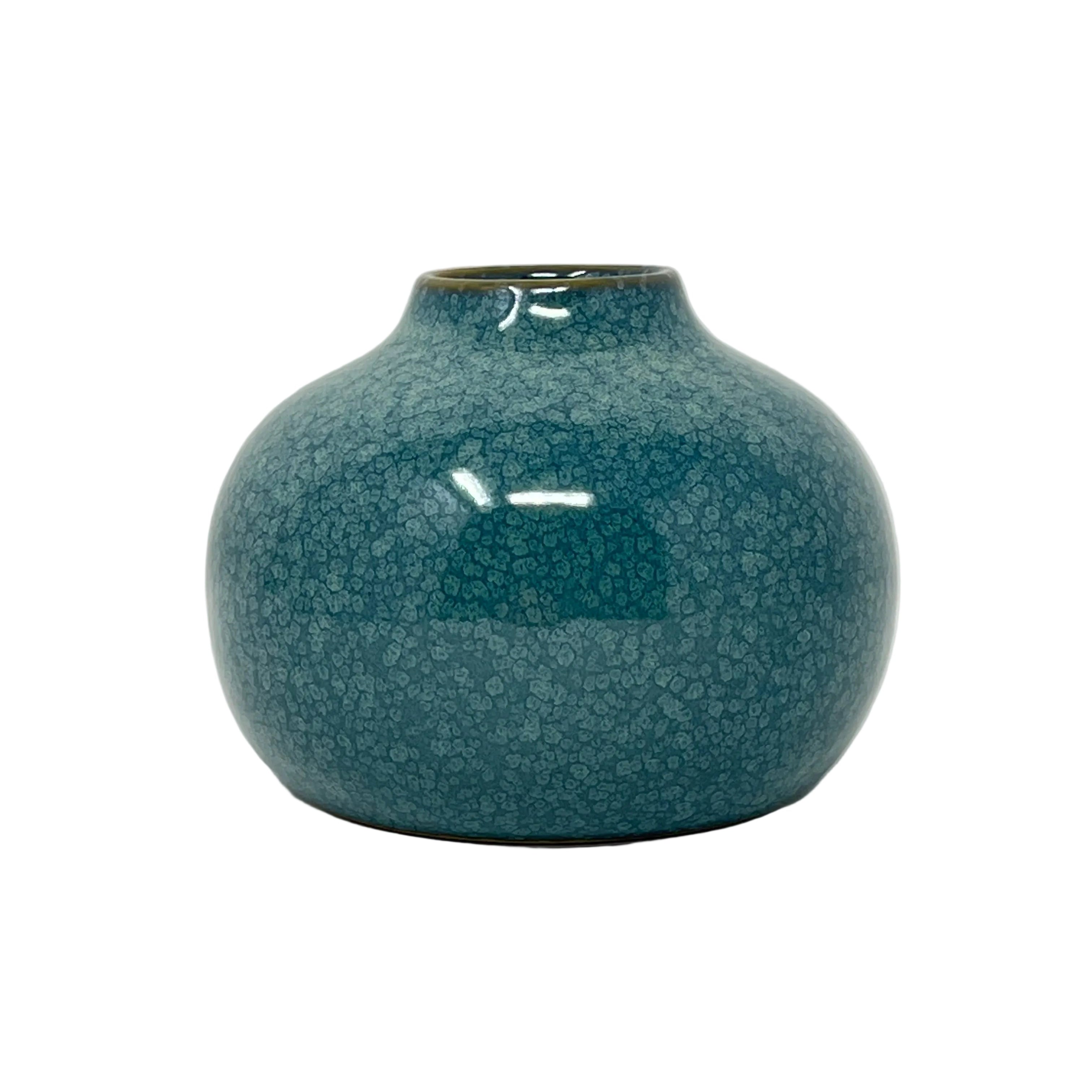 A small ceramic vase with a rounded bulbous body and a narrow neck, covered in a glossy teal-blue glaze with a subtle crackle texture, set against a plain light gray background.